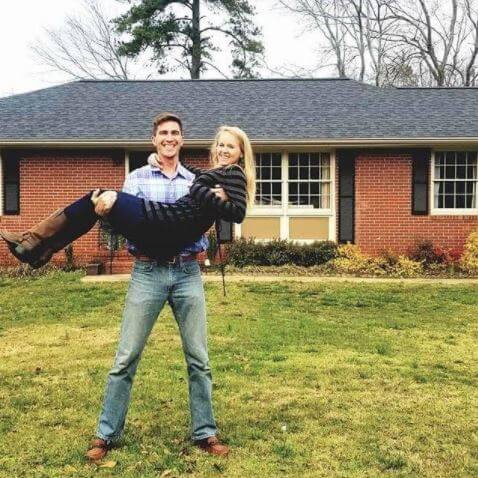 Chris Bruin holding his wife in front of his new home.